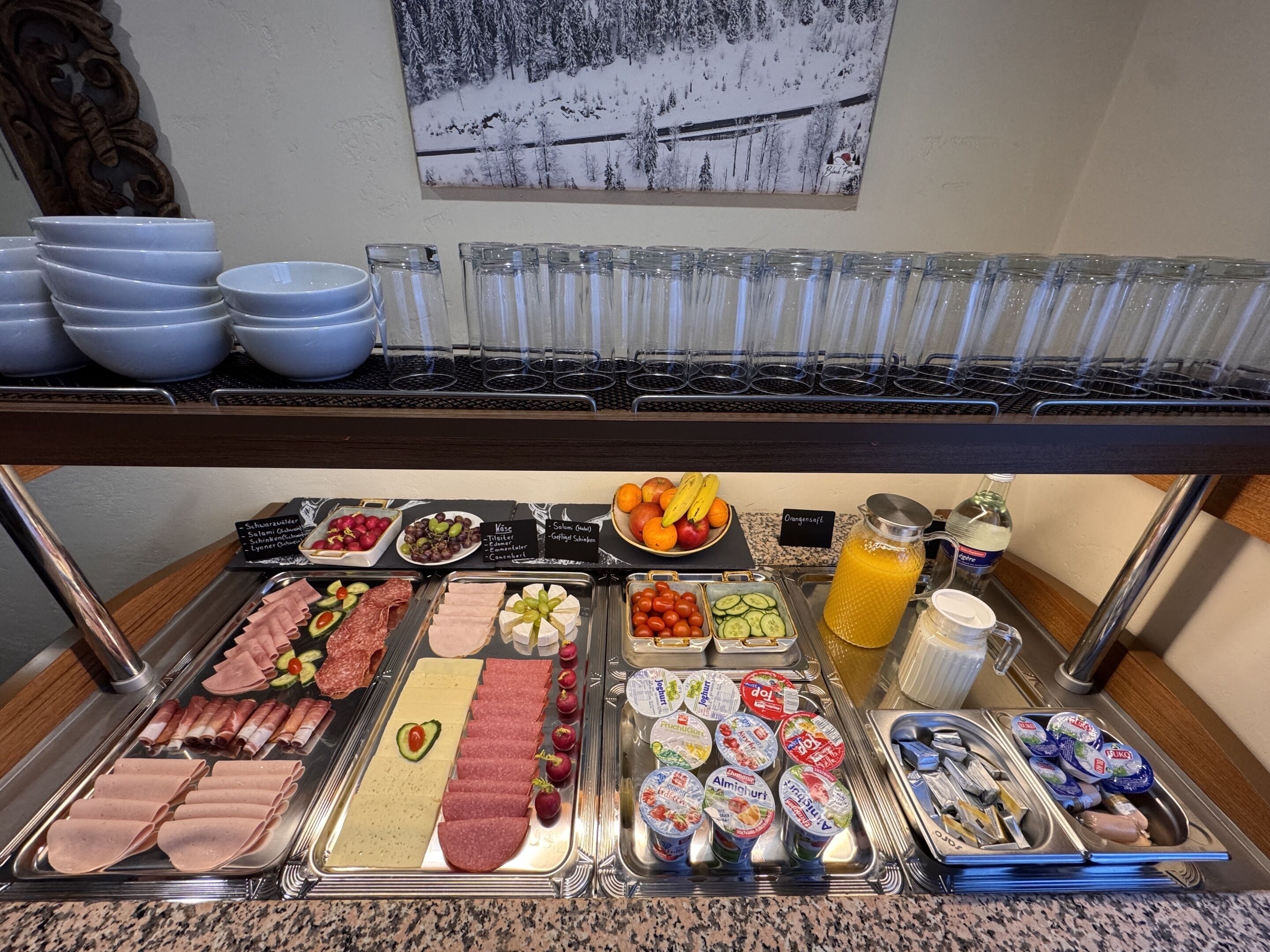 A buffet with various food items including meats, cheeses, fruits, and beverages.