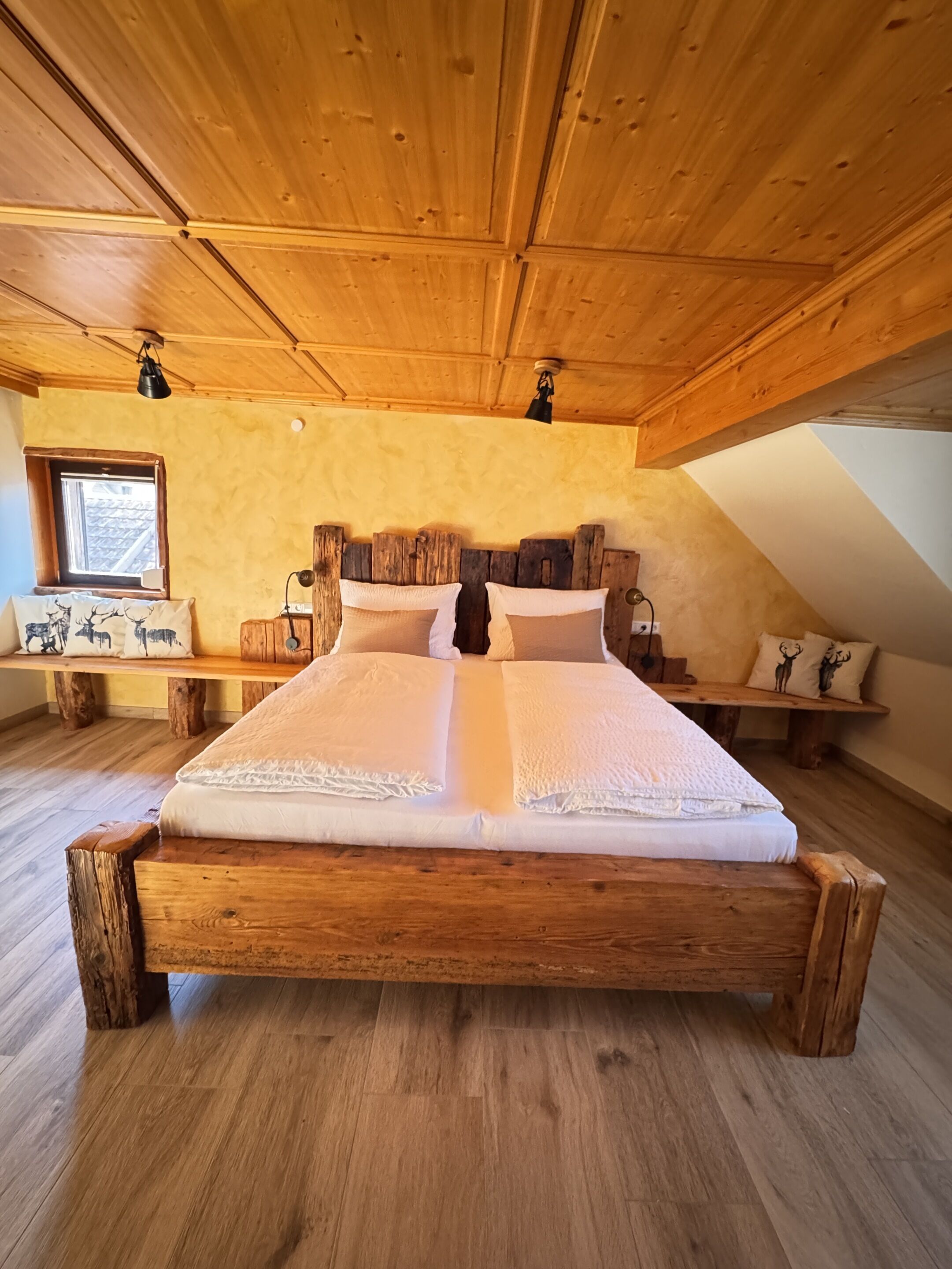 Uma cama de madeira num quarto com teto inclinado e janela.