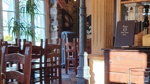 Een restaurantinterieur met houten tafels en stoelen, een bar en een grote decoratieve lamp.