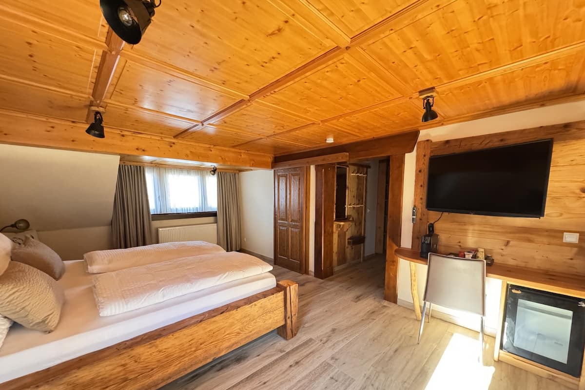 Habitación de cabaña de madera con una cama, un televisor y un escritorio pequeño.