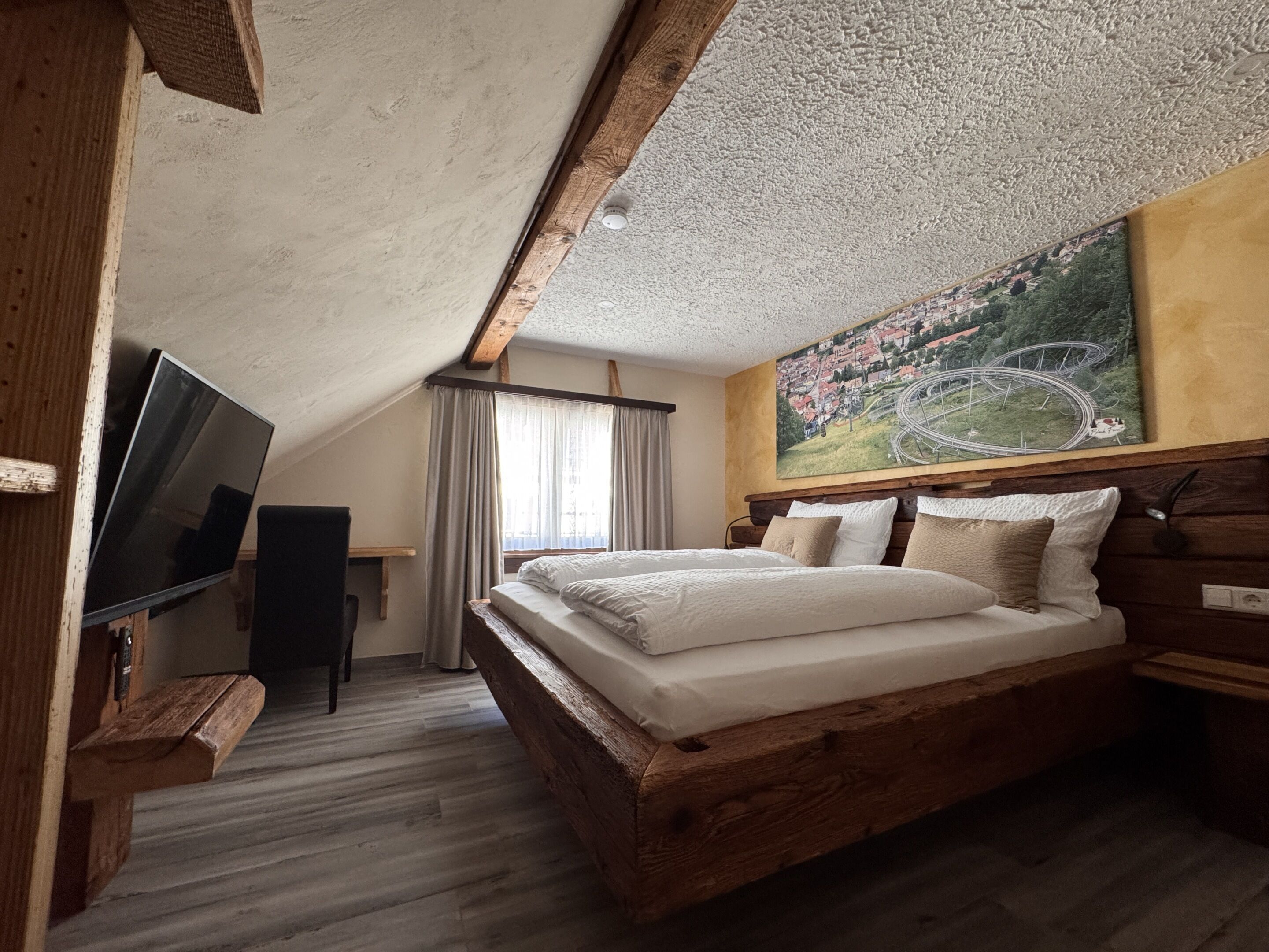 Ein Schlafzimmer mit einem hölzernen Bett, einem Flachbildfernseher und einem Landschaftsbild.