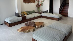 A modern living room with a sectional sofa, wooden coffee tables, and a staircase. - Front sea Mansion With Pool Maceio Paripueira (Paripueira)