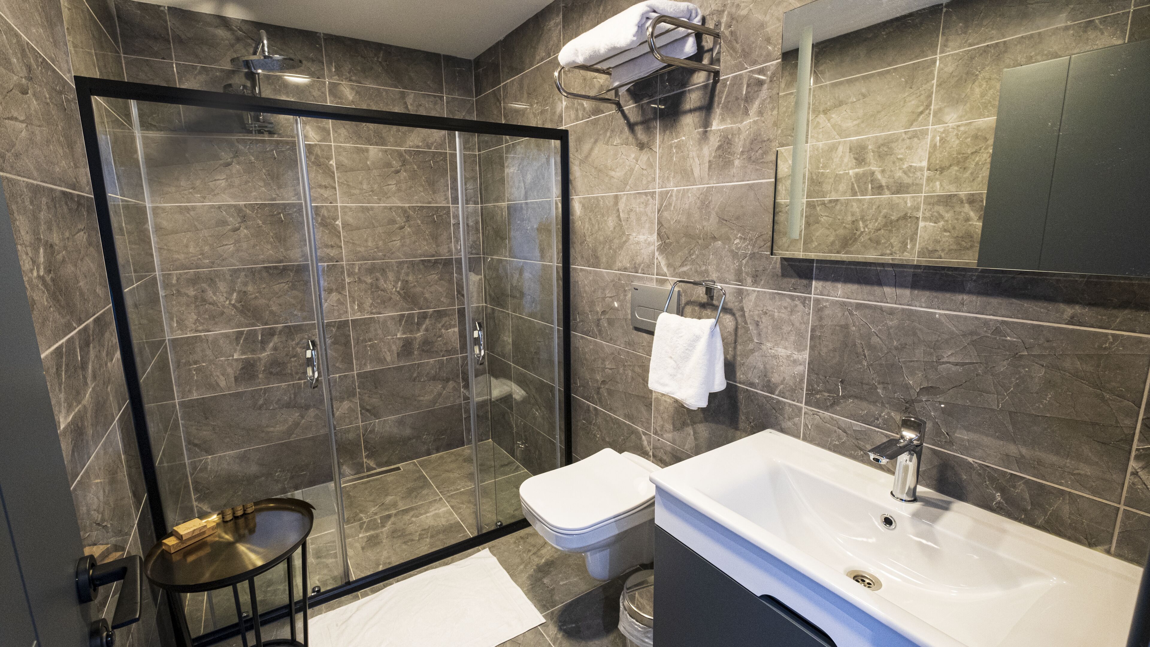 A modern bathroom with a glass-enclosed shower, a white sink, and a large mirror.