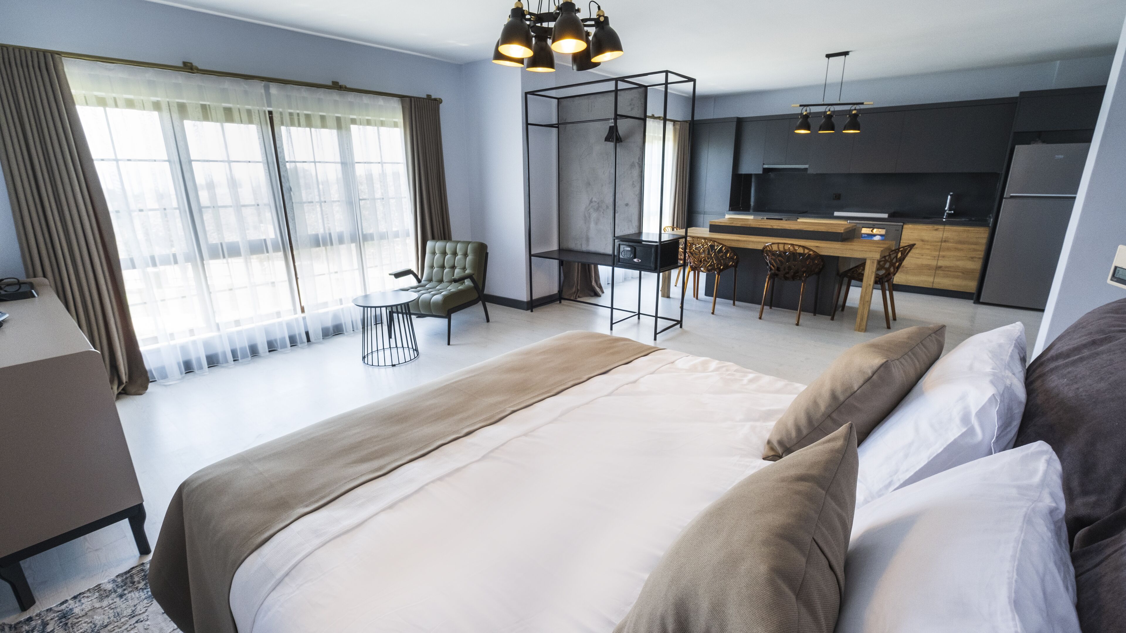 Une chambre d’hôtel moderne équipée d’un grand lit, d’un bureau et d’une kitchenette.