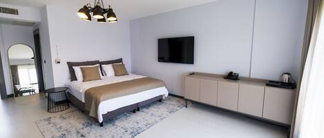 Una habitación de hotel moderna con una cama grande, un televisor de pantalla plana, un minibar y un espejo amplio.