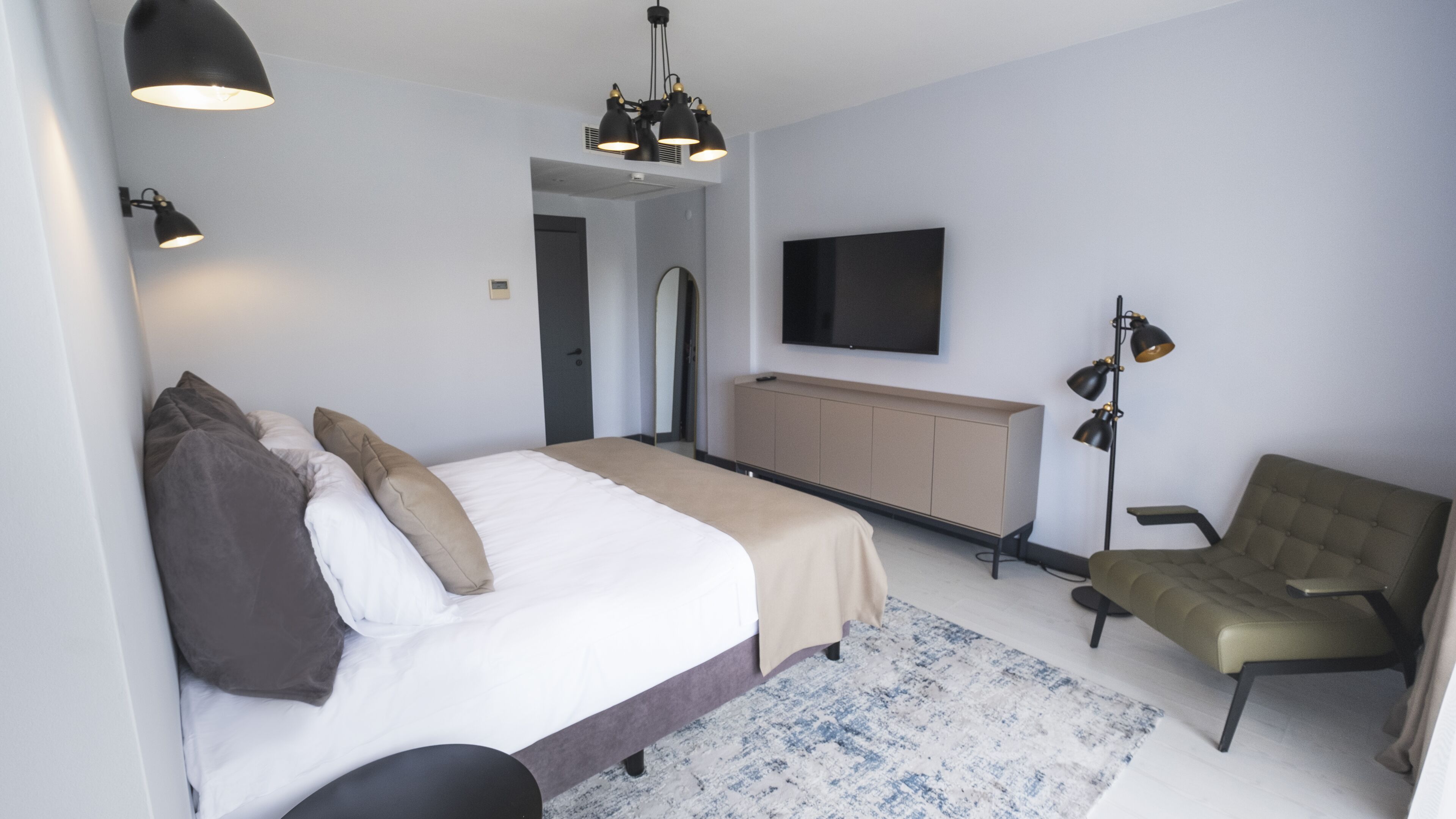 Una habitación de hotel moderna con una cama grande, televisión, escritorio y silla.