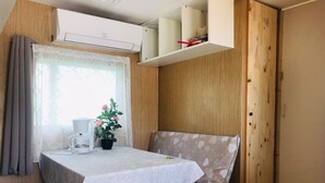 A compact RV interior with a dining table, a coffee maker, and a potted plant.
