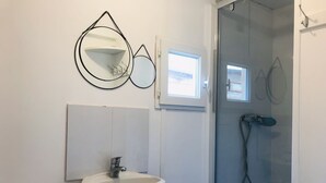 A bathroom with a white sink, a toilet, a glass shower enclosure, and two wall-mounted mirrors.