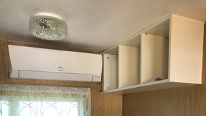 A compact kitchenette with a coffee maker, a small refrigerator, and a window with patterned curtains.