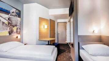 Ein Hotelzimmer mit zwei Betten, einem Wandgemälde und einem Flur, der zu einer Tür führt.