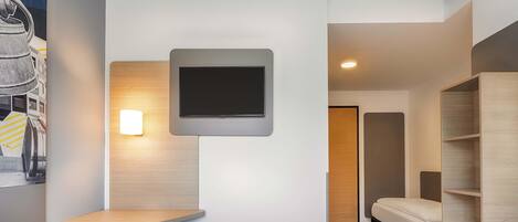 Une chambre d’hôtel moderne avec deux lits, un téléviseur à écran plat fixé au mur et une petite table.