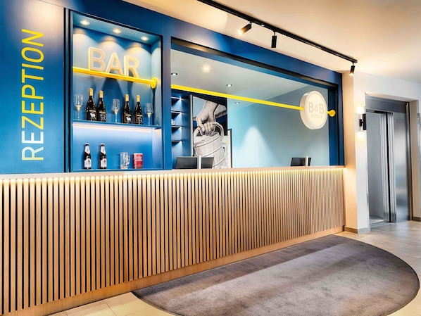 A reception area with a blue and yellow color scheme, a bar section with bottles and glasses, and a modern design with wooden slats.