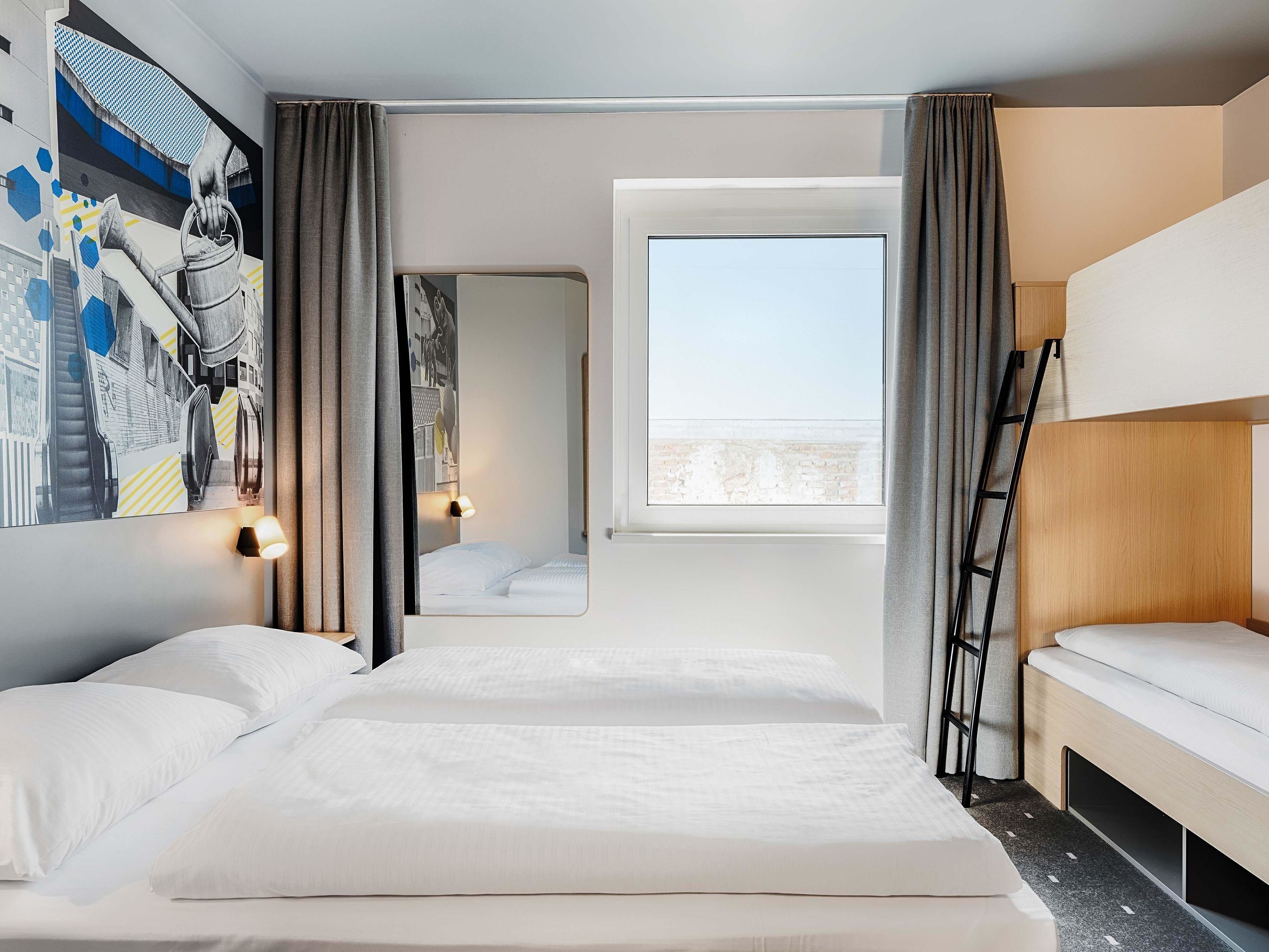 Ein Hotelzimmer mit zwei Betten, einem großen Fenster, einem Bild an der Wand und einer Leiter.