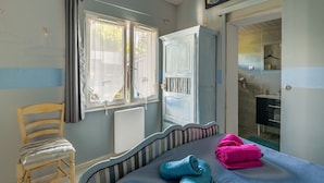 Ein Schlafzimmer mit Bett, Stuhl, Kleiderschrank und einem durchgegangenen Tür sichtbaren Badezimmer.