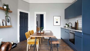 Una cocina moderna con un armario azul oscuro, una mesa de comedor de madera con dos sillas y un banco de madera.