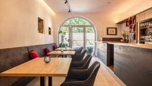 A restaurant with a bar area, seating with black chairs, and a large arched window.