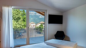 Un dormitorio con cama, televisión y balcón con vistas a la montaña.
