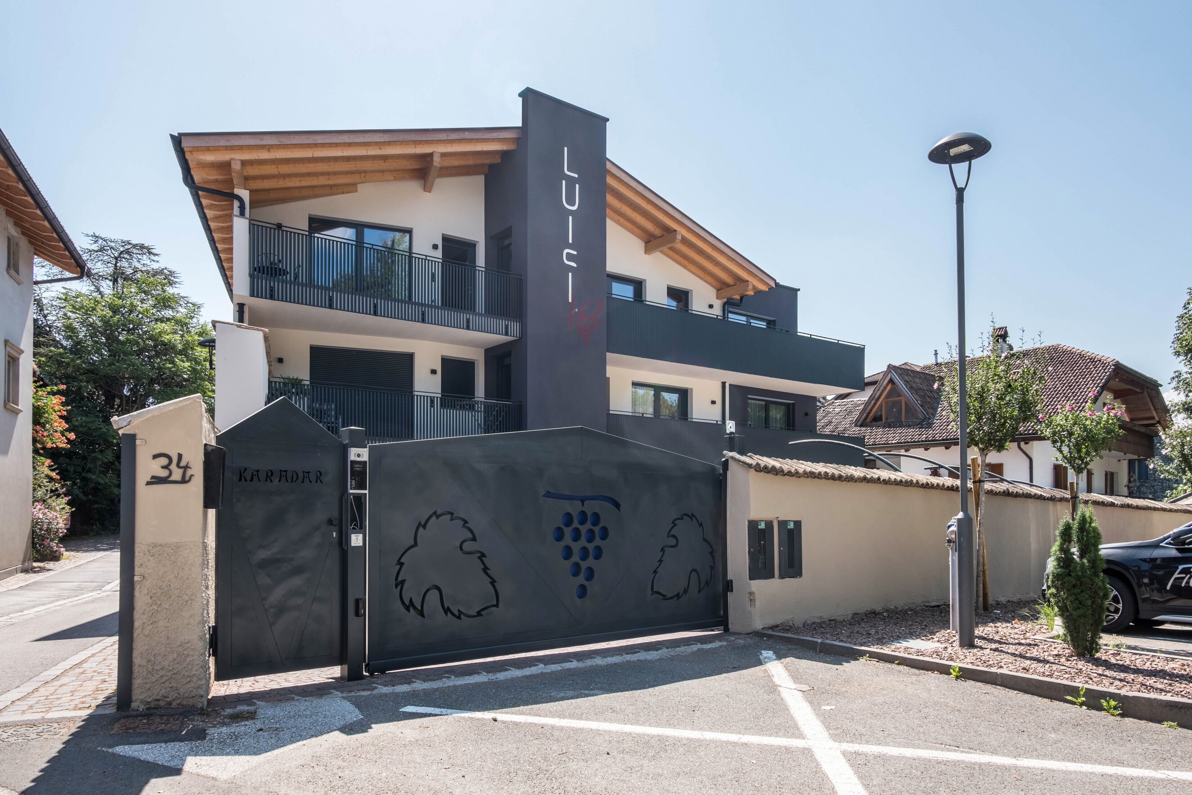 Un edificio moderno con un balcone, un cancello decorato con motivi di vite e il numero 34.