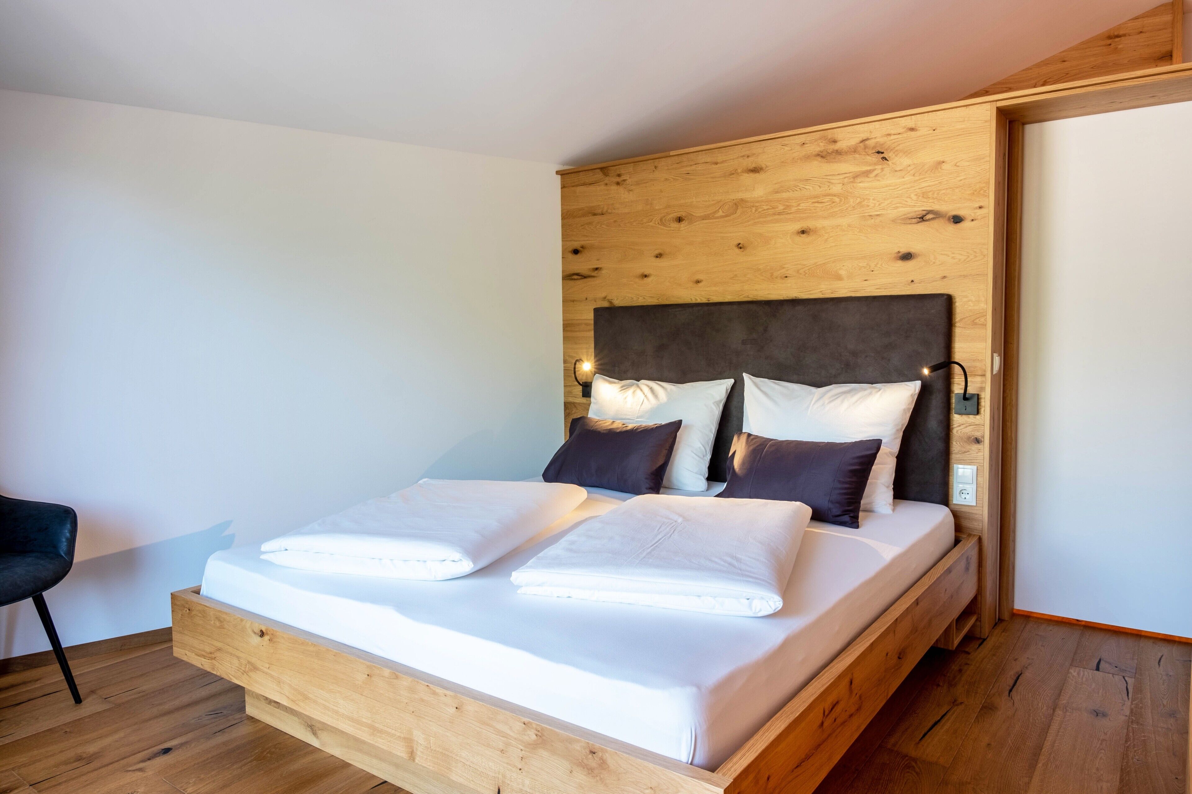 Un letto di legno con testiera, due cuscini e un comodino con una lampada.