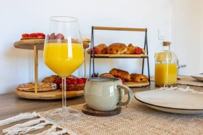 A breakfast setup with croissants, strawberries, a glass of orange juice, a mug, and a bottle of juice on a wooden table. - Quiet, warm apartment 5 minutes from the station (Besançon)