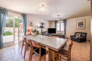 Un comedor con una mesa y sillas, un sofá, un televisor y una ventana con cortinas.