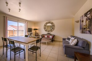 A living room with a dining table, chairs, a sofa, a TV, and a large mirror.
