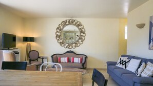 Un salon avec un canapé, une table à manger, un téléviseur et un miroir.