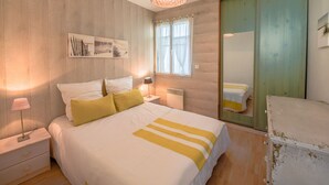 Une chambre à coucher avec un lit, des lampes de chevet, une fenêtre avec des rideaux, un miroir et un mur en bois.