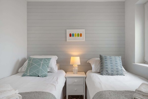 Habitación doble con dos camas, una mesita de noche con lámpara y un cuadro colgado en la pared de helado.