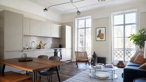 Eine moderne Küche mit weißen Schränken, einer Backspülwand im Fischgrätmuster und einem Essbereich mit Holztisch und Stühlen.