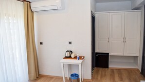 A small, clean room with a white wall, a wooden floor, a white table with a kettle and cups, and a white wardrobe. - Gökçeada Deep Breath (Gökçeada)