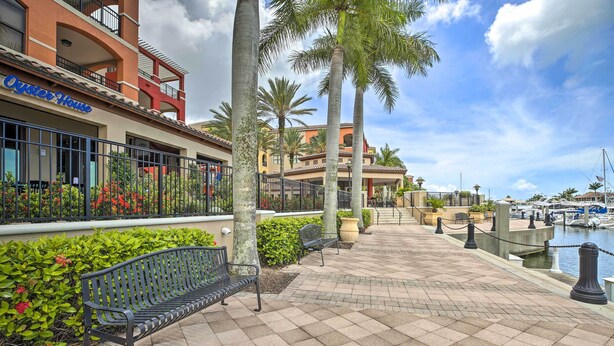 A waterfront promenade with a bench, palm trees, and a building with a sign reading "Oyster House". - Sunny Punta Gorda Condo w/ Golf Course View! (Punta Gorda)