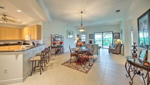 A spacious kitchen with a central island, dining area with a chandelier, and a living room with a sofa and large windows. - Sunny Punta Gorda Condo w/ Golf Course View! (Punta Gorda)
