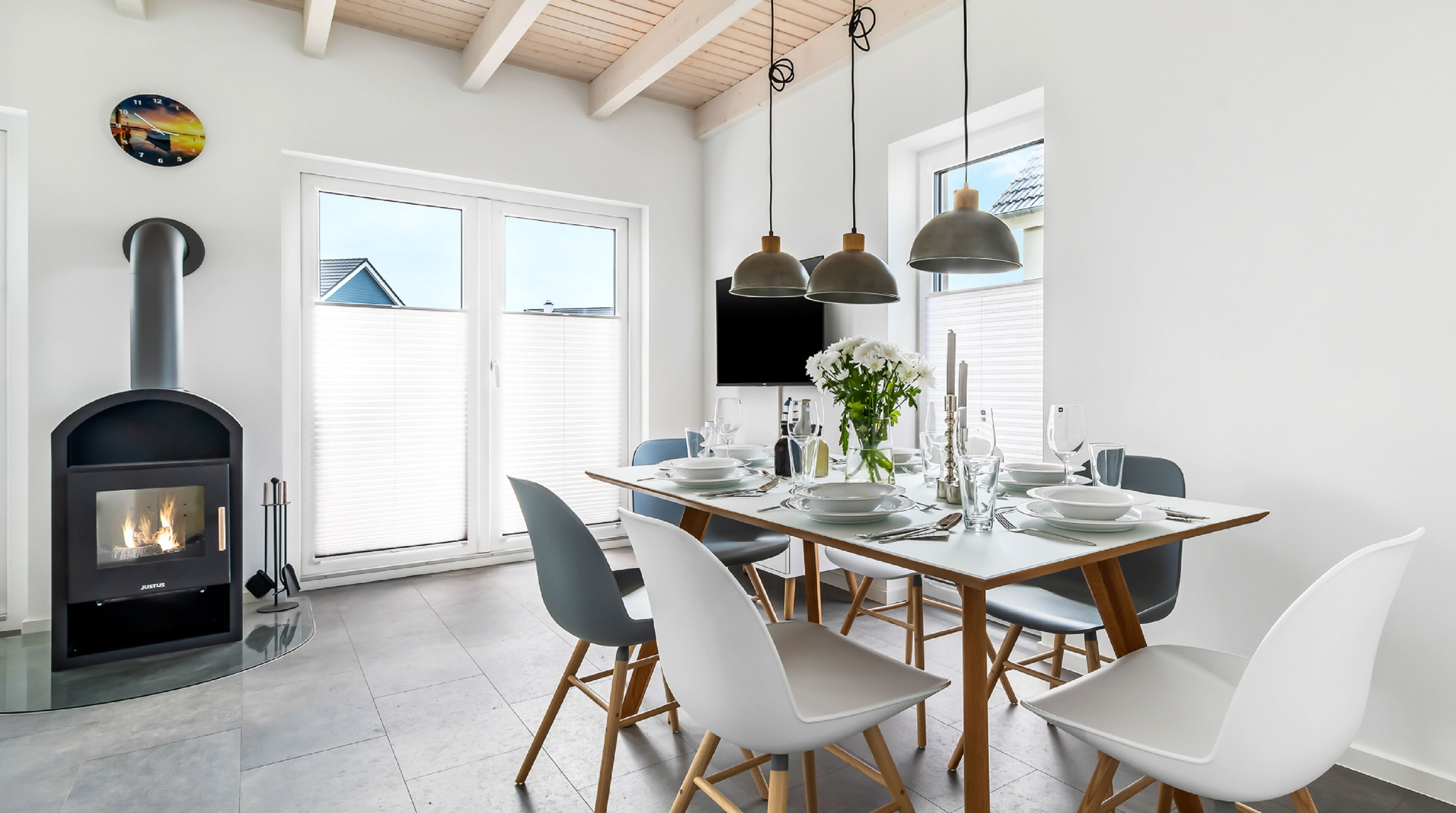 Un espace repas moderne doté d’un poêle à bois encastré, d’une table à manger blanche et de chaises.