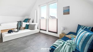 A modern, well-lit room with a loft bed, a sofa, and a window with blinds. - Bajo Lykke in the North Sea resort - close to the beach and the North Sea, fireplace, infrared sauna, Terra (Büsum)