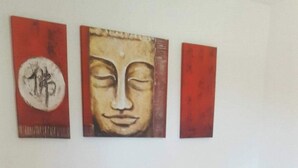 Quarto de hotel com cabeceira de madeira, colcha listrada e três obras de arte na parede.