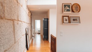 A hallway with wooden flooring, a stone wall, and a door leading to another room. - Biscoito Guest House (Viana do Castelo)