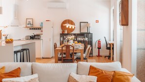 A modern kitchen with a dining area, white walls, and a wooden dining table. - Biscoito Guest House (Viana do Castelo)