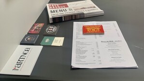 Pöydällä on ruokalista, käyntikortteja ja kehystetty valokuva.