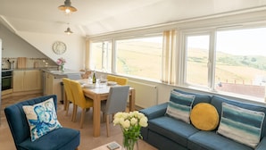 A modern kitchen with a dining area and a large window overlooking a field. - Higher Upover (Woolacombe)