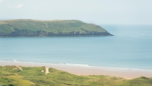 A coastal landscape with a beach, grassy hills, and a clear view of the sea. - Higher Upover (Woolacombe)