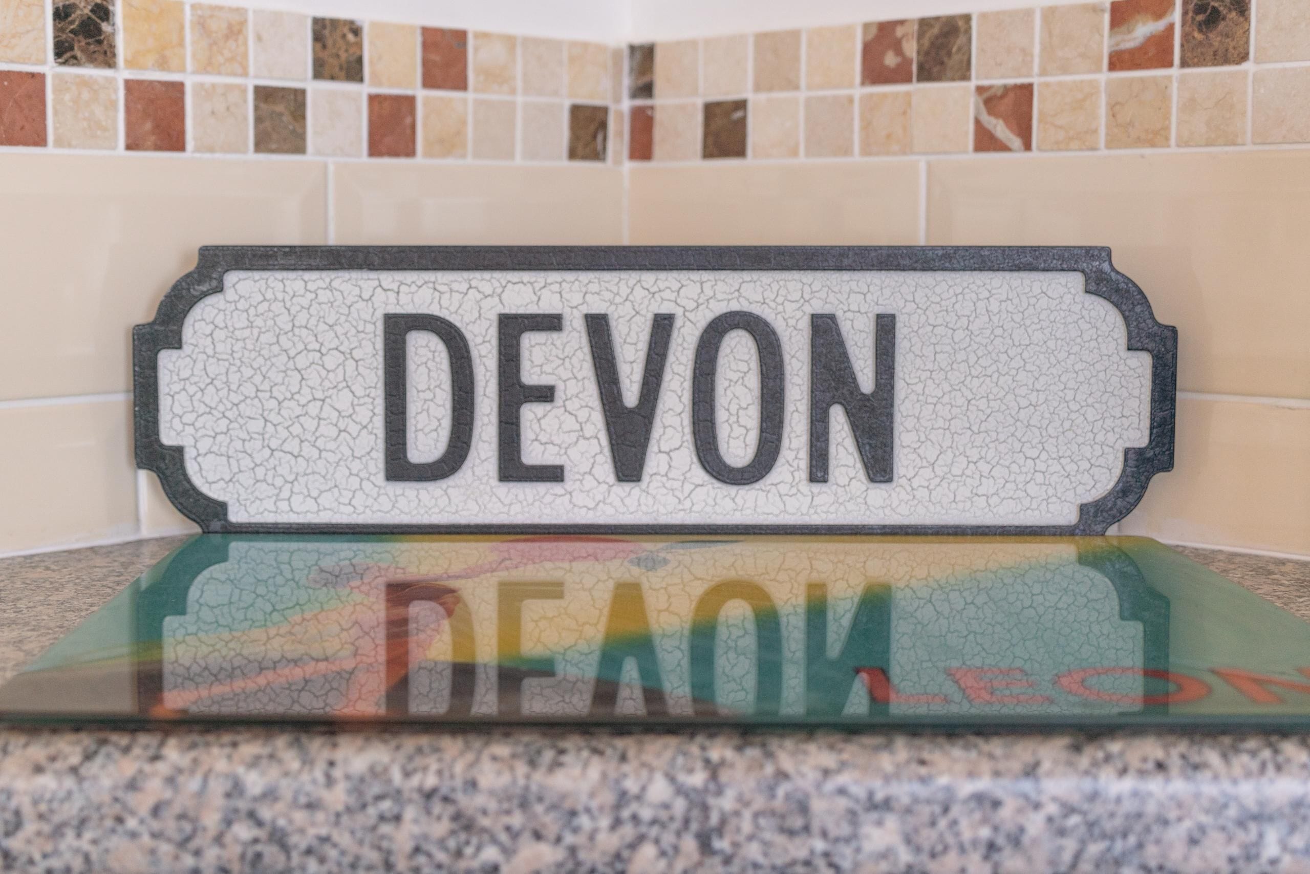 A sign with the word "DEVON" on a tiled wall.