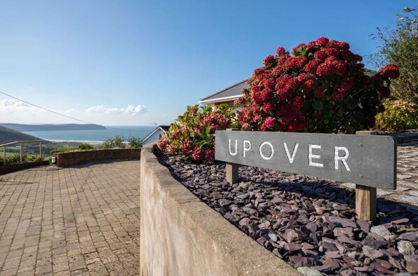 Un panneau indiquant « UPOVER », avec en arrière-plan un paysage côtier.