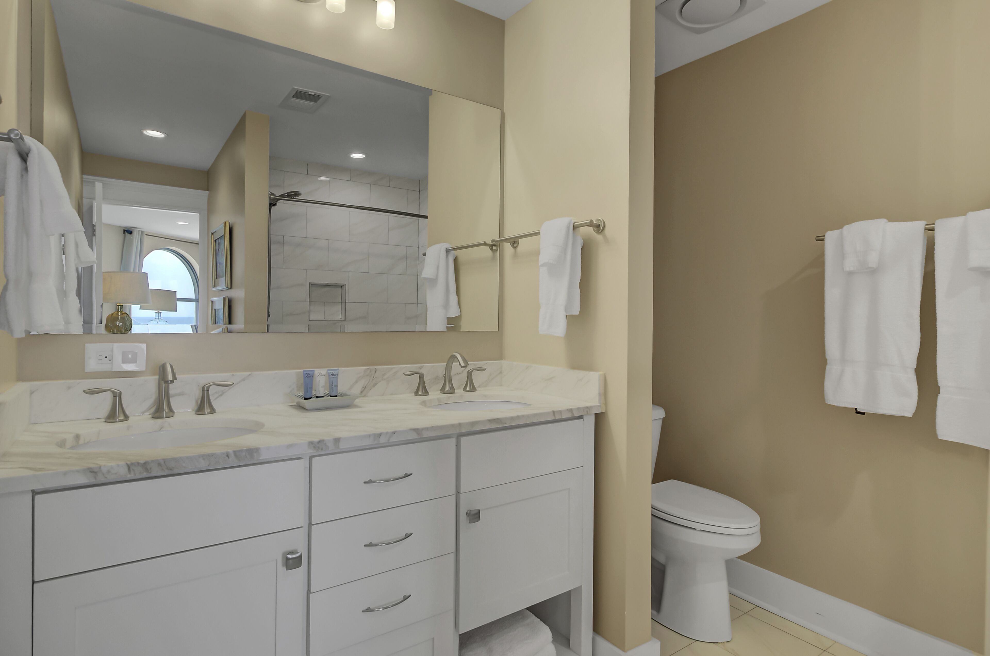 Une salle de bain moderne avec un lavabo en marbre, deux robinets, un grand miroir et des toilettes.