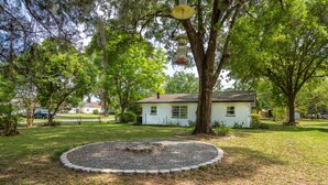 A house with a circular gravel area in front, surrounded by trees and a lawn.