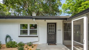 A white house with a black door, a number 20933, and a garden with plants and flowers.