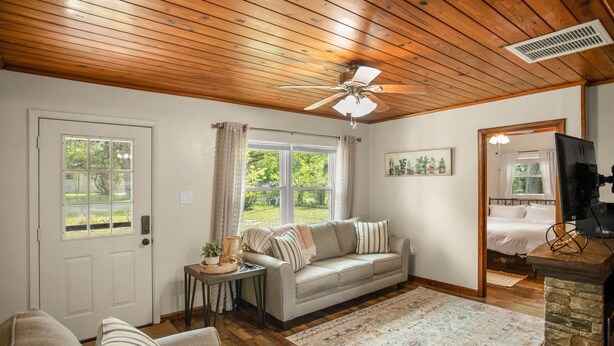 A cozy living room with a wooden ceiling, a sofa, a coffee table, and a rug.