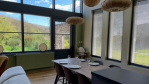 A dining area with a table set for four, large windows, and a view of greenery outside.