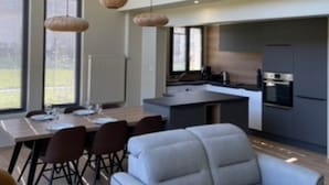 A modern kitchen with a central island, dark cabinetry, and stainless steel appliances.