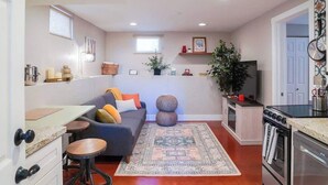 A compact living space with a sofa, coffee table, and kitchen area including a stove and refrigerator.